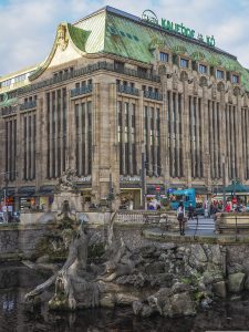 Die Szenerie zeigt das Gebäude von Galerie Kaufhof an der Düsseldorfer Königsallee – davor der Neptun Brunnen – Thomas Schoo kehrt bald dahin zurück.
