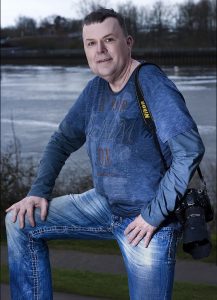 Ein Foto von meinem letzten Personal-Branding Shooting in Bremen – Hochformat mit meiner Lieblings-Jeans mit CAMP DAVID Longshirt – leger die Kamera über der Schulter mit Trageriemen! Strahlkraft vor der Kamera à la Thomas Schoo.